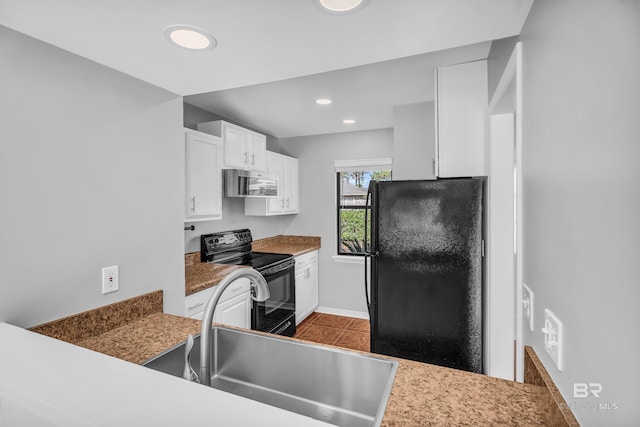 kitchen with light tile patterned flooring, sink, white cabinetry, and black appliances