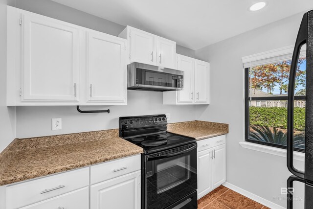 kitchen featuring white cabinets, black electric range oven, and dark stone countertops