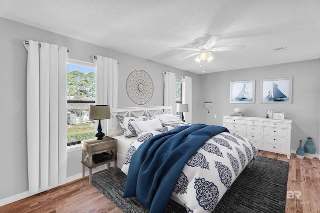 bedroom with hardwood / wood-style floors, ceiling fan, and a textured ceiling