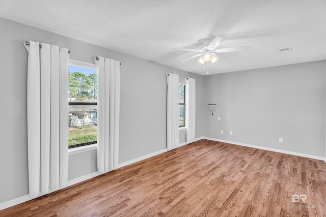 spare room with hardwood / wood-style flooring, ceiling fan, a textured ceiling, and a wealth of natural light