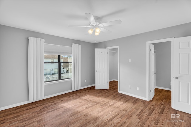 unfurnished bedroom with hardwood / wood-style flooring, ceiling fan, a walk in closet, and a closet