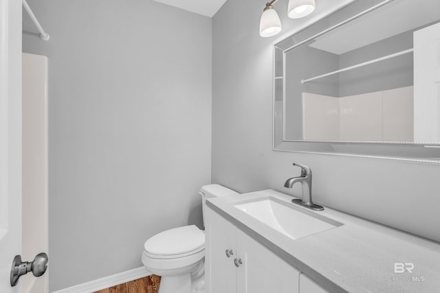 bathroom with hardwood / wood-style flooring, vanity, toilet, and a shower