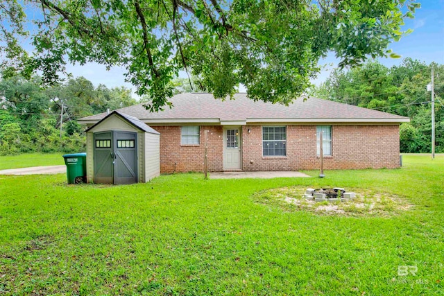 back of property with a lawn, a patio, a storage shed, and an outdoor fire pit