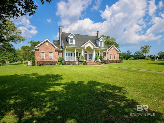 24235 County Road 87, Robertsdale, AL 36567 - cape cod-style house featuring covered porch, a chimney, a front lawn, and brick siding