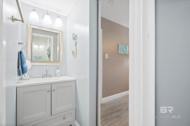 bathroom with hardwood / wood-style flooring, vanity, and a textured ceiling