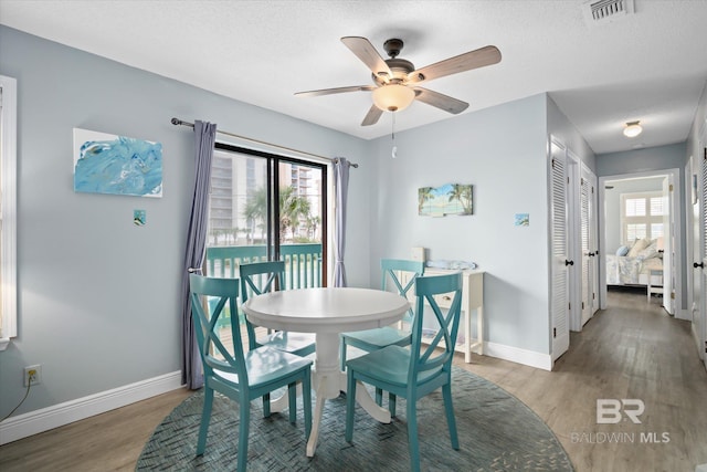 dining room featuring ceiling fan, dark wood-type flooring, and a textured ceiling