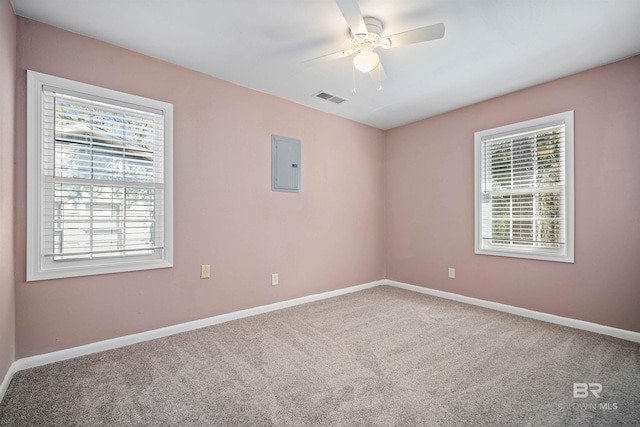 carpeted empty room featuring ceiling fan, a wealth of natural light, and electric panel