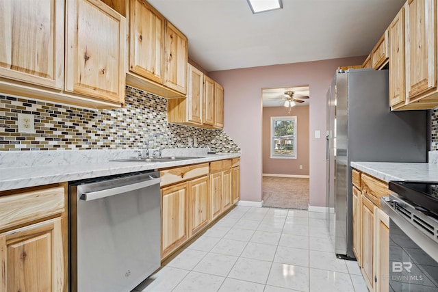 kitchen featuring light brown cabinets, ceiling fan, appliances with stainless steel finishes, sink, and light tile patterned flooring