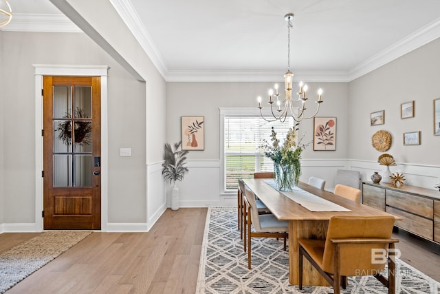 dining area with ornamental molding, light hardwood / wood-style flooring, and a chandelier