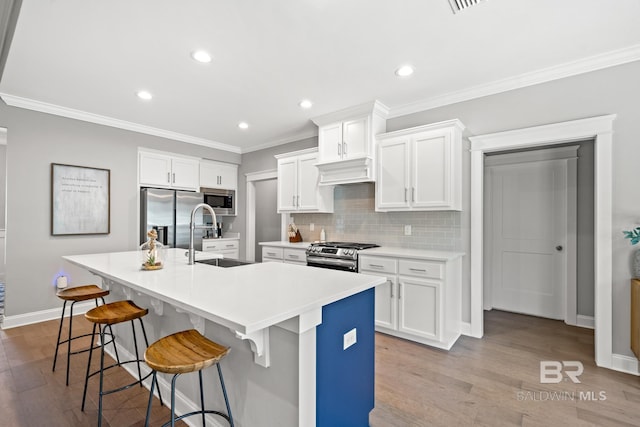 kitchen with light hardwood / wood-style floors, a kitchen island with sink, a breakfast bar, stainless steel appliances, and sink