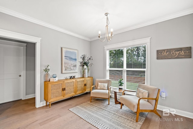 sitting room featuring light wood-type flooring, ornamental molding, and a chandelier