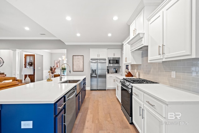 kitchen with appliances with stainless steel finishes, white cabinetry, sink, blue cabinets, and a kitchen island with sink