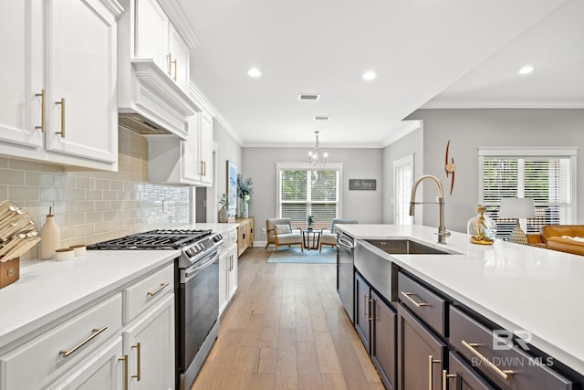 kitchen with white cabinets, hanging light fixtures, light hardwood / wood-style flooring, stainless steel appliances, and sink