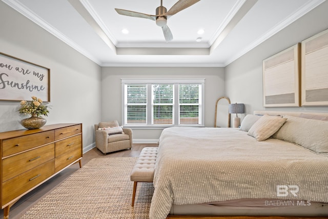 bedroom featuring hardwood / wood-style floors, ceiling fan, a raised ceiling, and ornamental molding