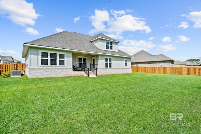 rear view of house with cooling unit and a lawn