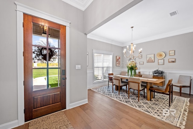 entrance foyer featuring crown molding, an inviting chandelier, and hardwood / wood-style flooring