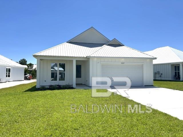 1257 Dorado Way, Gulf Shores, AL 36542 - modern inspired farmhouse featuring board and batten siding, concrete driveway, a front yard, an attached garage, and metal roof