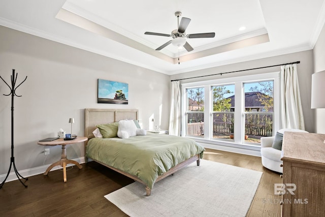 bedroom featuring crown molding, baseboards, a tray ceiling, wood finished floors, and a ceiling fan