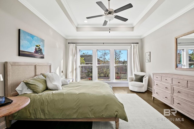 bedroom featuring a ceiling fan, dark wood-type flooring, a tray ceiling, and ornamental molding