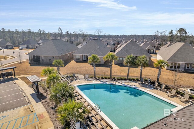 community pool with a patio, fence, and a residential view