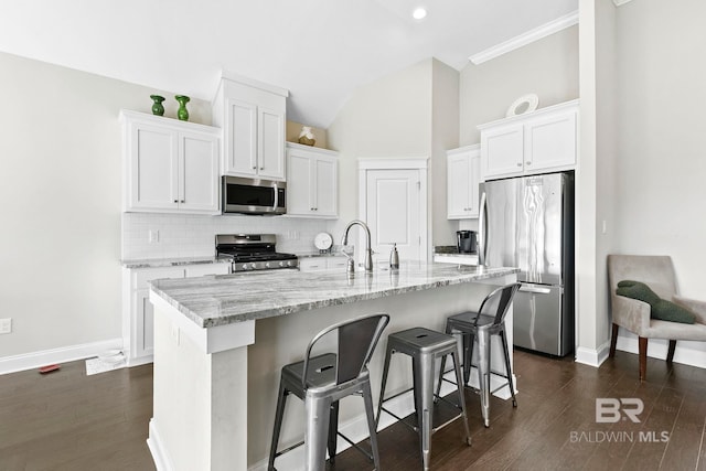 kitchen featuring dark wood finished floors, backsplash, appliances with stainless steel finishes, and white cabinetry