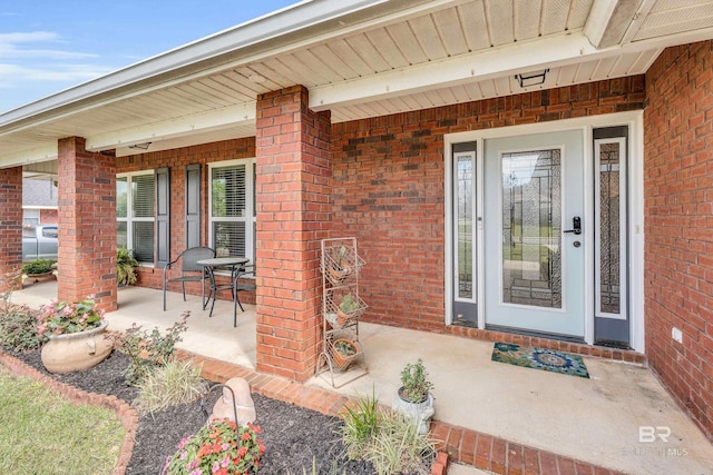 doorway to property featuring brick siding and covered porch