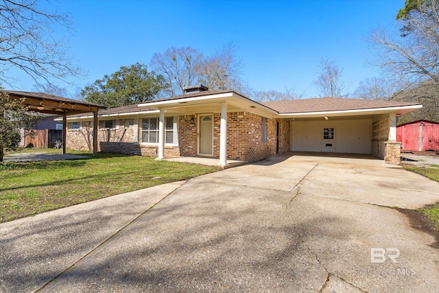 view of front of property with brick siding, concrete driveway, an outbuilding, fence, and a front yard