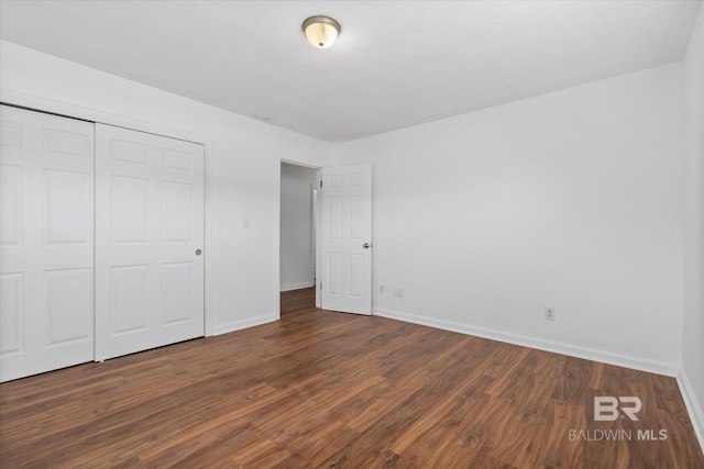 unfurnished bedroom featuring a closet, baseboards, and wood finished floors