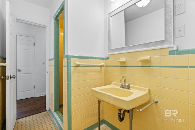 bathroom with tile patterned floors, a shower stall, tile walls, and wainscoting