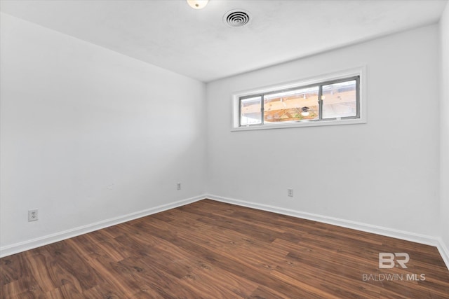 spare room with baseboards, visible vents, and dark wood finished floors