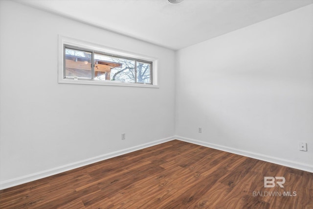 empty room featuring dark wood-style floors and baseboards