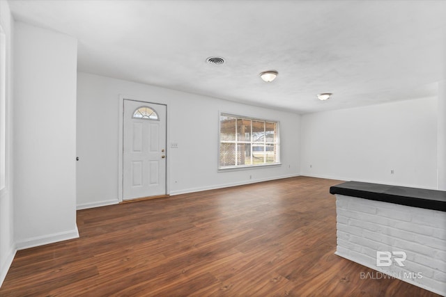 unfurnished living room featuring wood finished floors, visible vents, and baseboards