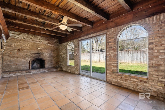 unfurnished living room with wooden ceiling, brick wall, ceiling fan, beamed ceiling, and a brick fireplace