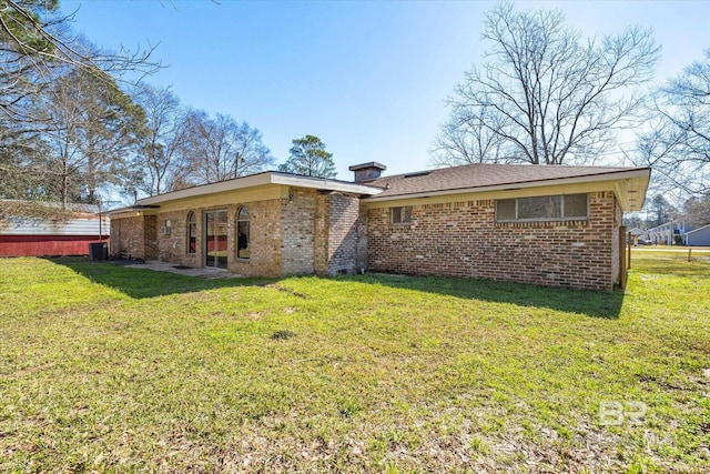 rear view of house with a lawn and brick siding