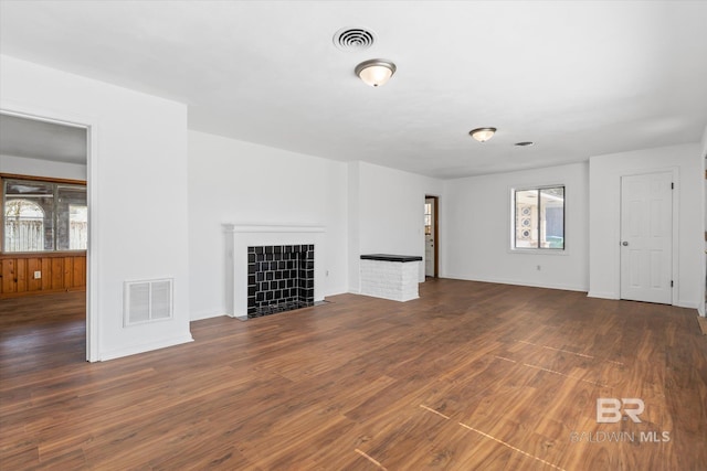 unfurnished living room featuring a fireplace, wood finished floors, visible vents, and baseboards