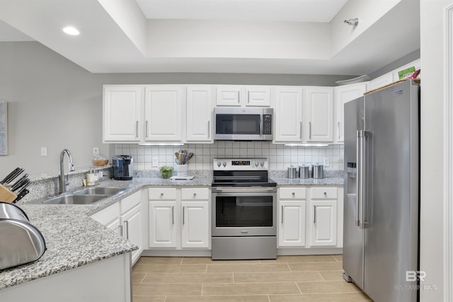 kitchen with light stone counters, stainless steel appliances, sink, and white cabinets