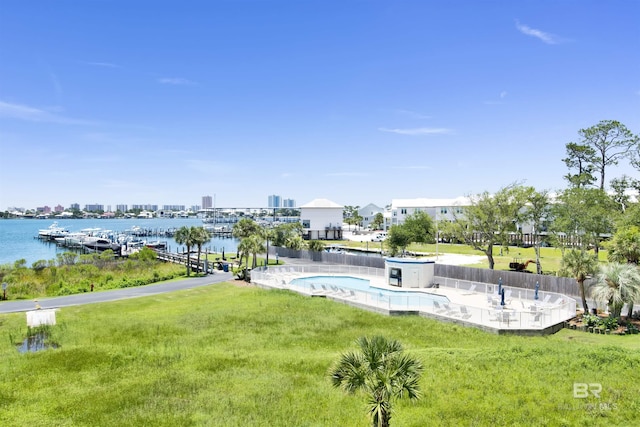 view of pool with a water view and a yard