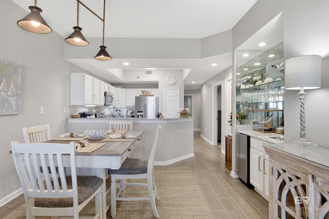 kitchen with white cabinetry, light stone counters, decorative light fixtures, appliances with stainless steel finishes, and backsplash