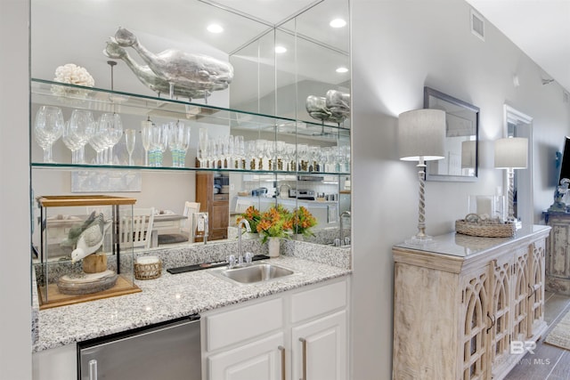 bar with dishwasher, light stone countertops, sink, and white cabinets