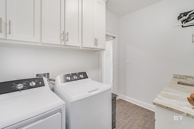 washroom with cabinets, washer and dryer, and wood-type flooring