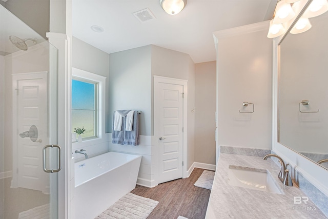 bathroom with hardwood / wood-style floors, vanity, and shower with separate bathtub