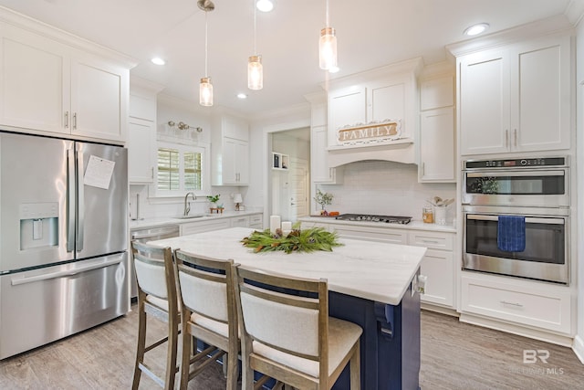 kitchen with white cabinets, decorative light fixtures, a kitchen island, and stainless steel appliances