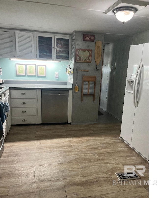 kitchen with dishwasher, white cabinetry, and white fridge with ice dispenser