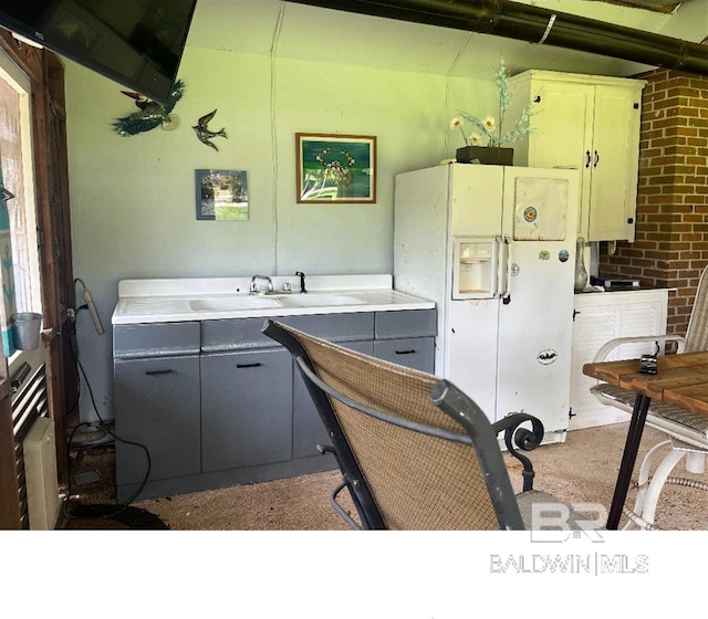 kitchen with gray cabinets, white fridge with ice dispenser, and sink