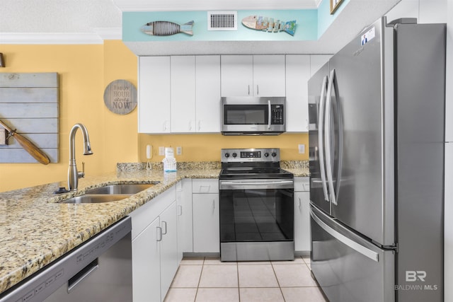 26750 Perdido Beach Blvd Unit 708, Orange Beach, AL 36561 - kitchen featuring appliances with stainless steel finishes, crown molding, white cabinets, light tile patterned floors, and light stone counters