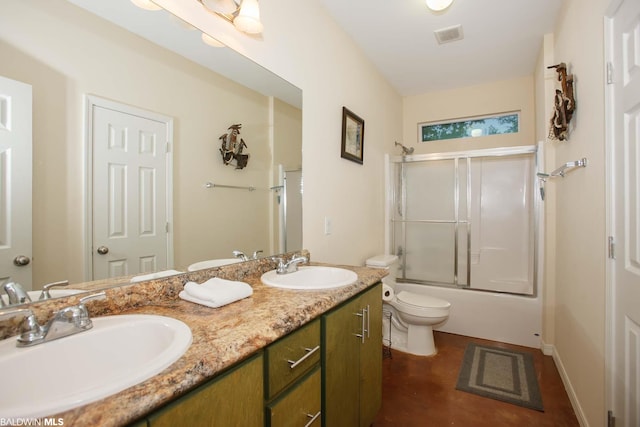full bathroom with bath / shower combo with glass door, toilet, and dual vanity