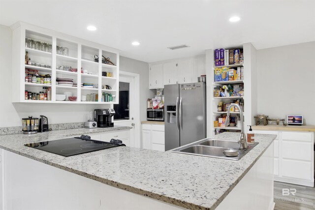 kitchen with white cabinetry, open shelves, visible vents, appliances with stainless steel finishes, and a sink