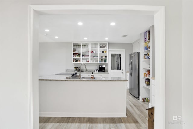 kitchen featuring open shelves, freestanding refrigerator, a peninsula, white cabinetry, and light wood finished floors