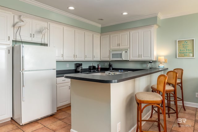 kitchen featuring kitchen peninsula, white appliances, light tile flooring, a kitchen bar, and white cabinetry