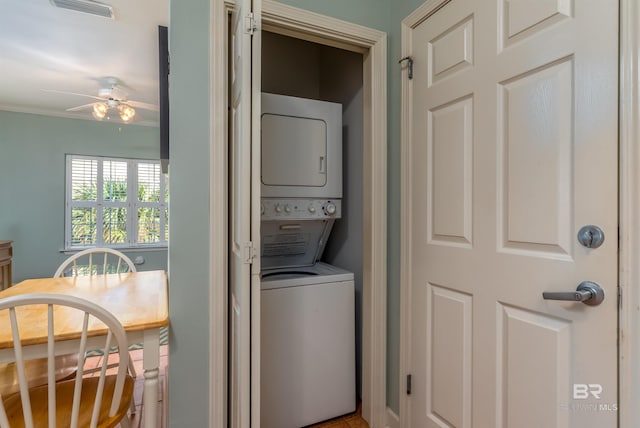 laundry room featuring stacked washing maching and dryer, ornamental molding, and ceiling fan